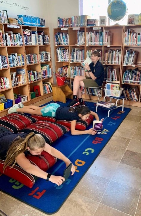 Students laying on the floor reading in a library